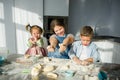 Three children prepare something from the dough.