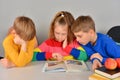 Three children read a book and do their homework assigned at school