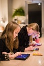 Three children at a restaurant using iPads