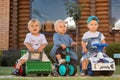 Three children ride on toy vehicles in the backyard. Royalty Free Stock Photo