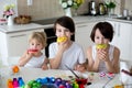 Three children, sibling brothers, painting easter eggs for decoration