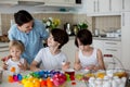 Three children, sibling brothers, painting easter eggs for decoration, mom helping them