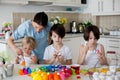 Three children, sibling brothers, painting easter eggs for decoration, mom helping them