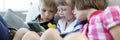 Three children sit on couch and hold telephone. Royalty Free Stock Photo