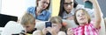 Three children sit side by side on couch and play games on phone. Royalty Free Stock Photo