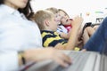 Three children sit side by side on couch and play on smartphones. Royalty Free Stock Photo