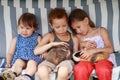 Three children are sitting in a hammock and playing her guinea pig pet animal Royalty Free Stock Photo