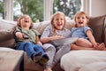 Three Children Sitting On Sofa At Home Laughing And Watching TV With Popcorn Royalty Free Stock Photo