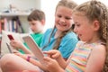 Three Children On Sofa At Home Playing With Digital Devices