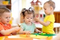 Three children playing with plasticine in nursery or creche