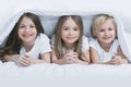 Three children under blanket