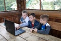 Three children using laptop in gazebo