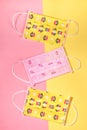 Three childrens pink and yellow medical masks on yellow with pink background. Covid-2019. Vertical orientation. Royalty Free Stock Photo