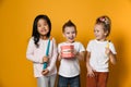 Three childrens with toothbrushes and a kissuos mock-up with zooms stand over yellow background Royalty Free Stock Photo