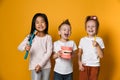 Three childrens with toothbrushes and a kissuos mock-up with zooms stand over yellow background Royalty Free Stock Photo