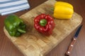 Three chili bell pepper on a wooden cutting board with knife on the table.