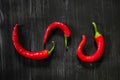 Three chili peppers on black background, top view.