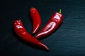 Three chilli pepper isolated on black slate board. Flat lay.