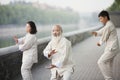 Three Chinese People Practicing Tai Ji Outdoors