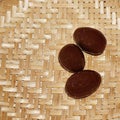 Three chocolate almonds on wicker background