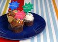 Three chocolate frosted cupcakes on a blue plate with Royalty Free Stock Photo