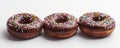 Three chocolate frosted donuts with sprinkles on white background Royalty Free Stock Photo