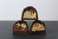 three chocolate glazed case candies with praline chocolate filling and nuts whole and crushed peanuts and hazelnuts lie