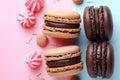 Three chocolate and vanilla macarons are displayed on a pink background, AI