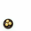 Three chocolates, wrapped in golden foil, lie on a brown porcelain saucer. Royalty Free Stock Photo