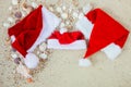 Three christmas hats on the beach. Santa hat the sand near shells. Family holiday. New year vacation. Copy space. Frame. Top view Royalty Free Stock Photo