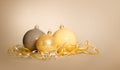 Three Christmas New Year balls of gray gold and yellow lie near a serpentine on a yellow beige background. Royalty Free Stock Photo