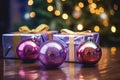 three christmas ornaments on a wooden table with a christmas tree in the background Royalty Free Stock Photo