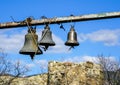 Three church bells of small, medium and large size hanging in chains against a blue sky whit white clouds Royalty Free Stock Photo