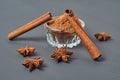 Three cinnamon sticks near glass bowl full of powder and scattered stars of anise lies on dark scratched desk on kitchen Royalty Free Stock Photo