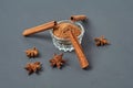 Three cinnamon sticks near glass bowl full of powder and scattered stars of anise lies on dark scratched desk on kitchen Royalty Free Stock Photo