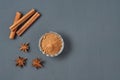 Three cinnamon sticks near glass bowl full of powder and scattered stars of anise lies on dark scratched desk on kitchen Royalty Free Stock Photo