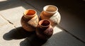 Three clay pots with etched patterns in sunlight on stone floor Royalty Free Stock Photo