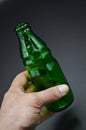 Three green empty glass soda bottles and hand, isolated on gray background Royalty Free Stock Photo