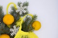 Three clementines in yellow eco string shopping bag with Christmas tree branch and snowflakes on white background with copying