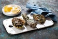 Three closed fresh raw oysters on a white ceramic serving board