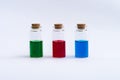 Three closed vials with colored contents on a white background. Green, red, blue.