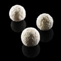 Three coconut truffles isolated on black background