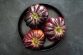 Three coeur de boeuf tomatoes (translation: beefsteak tomatoes) on black plate and background Royalty Free Stock Photo