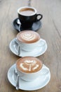 Three cofffee cup with latte art rose flower shape in the first cup another cup is hearth and leaf pattern,the last in black cup Royalty Free Stock Photo