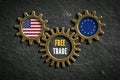 Three cogwheels on slate background with the flags of USA and the EU and the words `free trade` in the middle