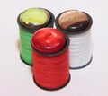 Three coils of red, green and white wire with buttons on top. Sewing accessories on a white background. Royalty Free Stock Photo