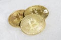 Three coins of crypto-currency bitcoin lie on white snow. Royalty Free Stock Photo