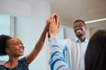 Three colleagues give high five in office, celebrate success, happy teamwork