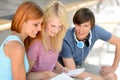 Three college friends studying looking into book Royalty Free Stock Photo