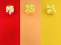 Three colour gift boxes with a yellow satin ribbon bow on their same color background. Royalty Free Stock Photo